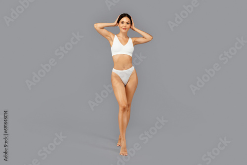 Happy european slim millennial woman in white underwear with perfect body, enjoy body care © Prostock-studio