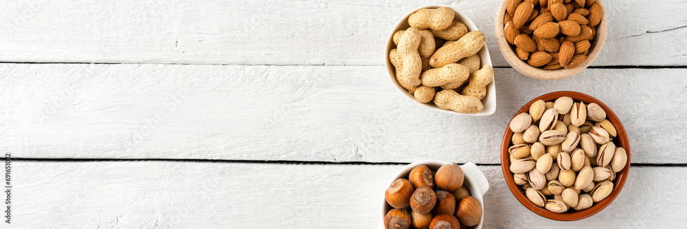 Nuts: almonds, pistachios, peanuts, hazelnuts and cashews in bowls on white wooden background with copyspace Nuts: almonds, pistachios, peanuts, hazelnuts and cashews in bowls on white wooden background with copyspace