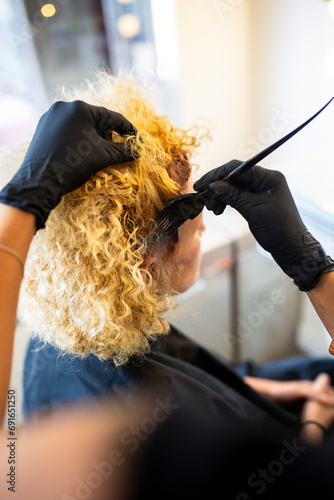 Stylist applying hair dye to client's curly hair