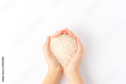 Overhead shot of woman’s hands holding white rice grains isolated on white background photo