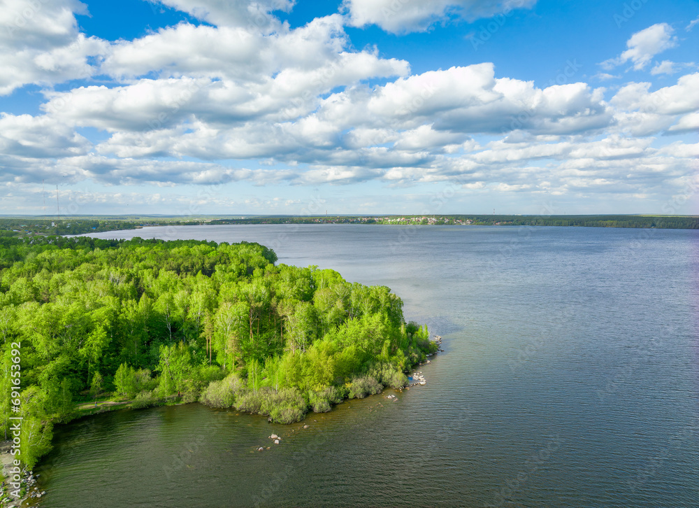 Aerial view of lake or river green shore with forest. Summer season.