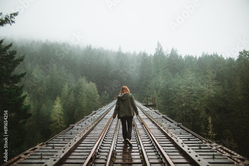 Woman walking in misty forest railroad on Vancouver Island photo