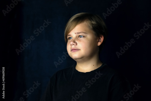 A concise portrait of a European boy. Portrait on a dark background.