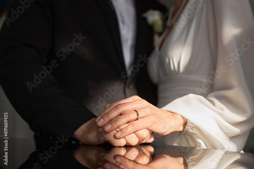 Close up of married senior couple holding hands in church with focus on wedding rings in sunlight photo