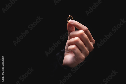 Female hand with a ring on the background. Golden ring with one large diamond in hand, held in fingers to camera