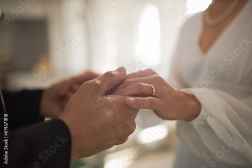 Closeup of mature bride and groom holding hands with focus on golden wedding rings, copy space