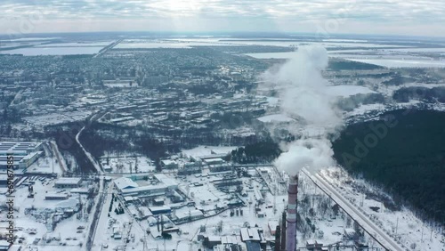 Smoking chimney on the background of the city in winter. Environmental pollution from emissions into the atmosphere. Aerial view of atmospheric emissions. Ukraine 2022, the city of Shostka. photo