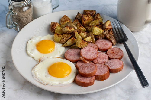 breakfast plate of  fried eggs and kielbasa with home fries photo