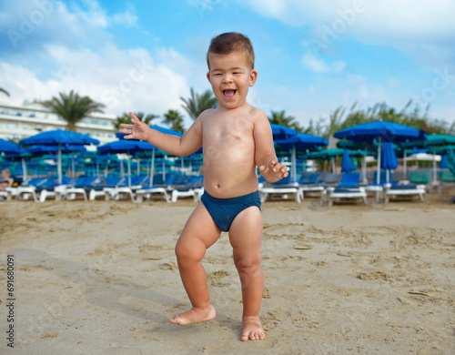 Small cute baby playing on the beach.Child in nature with beautiful sea, sand and blue sky.Happy child on vacation at sea running in the beach.Happy lifestyle childhood concept,Cyprus, Ayia-napa