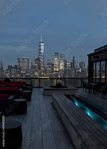 rooftop bar restaurant with views of downtown manhattan skyline (seats and bench) new york city skyscrapers (luxury travel) nyc view from roof deck at dusk (blue hour) night twilight (office buildings