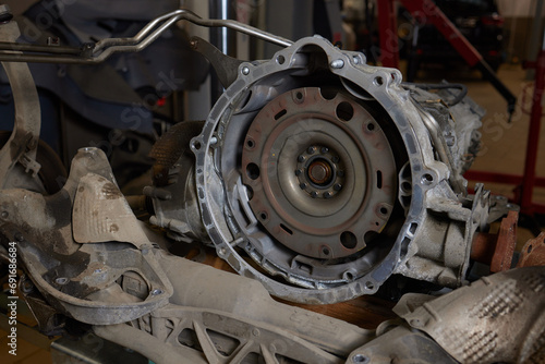 Closeup disassembled car automatic transmission gear part on workbench at garage or repair factory station for fix service or maintenance. Vehicle part detail. Complex industrial mechanism background