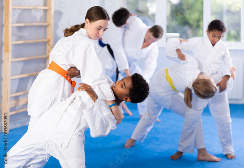 Boy and girl judokas train judo in group in studio..