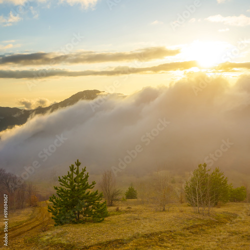 mountain valley in dense mist and clouds at the sunset