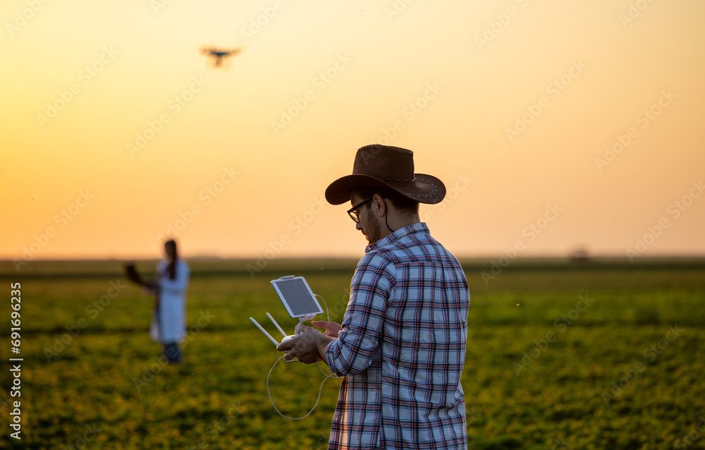 Fototapeta premium Farmer driving drone above farmland
