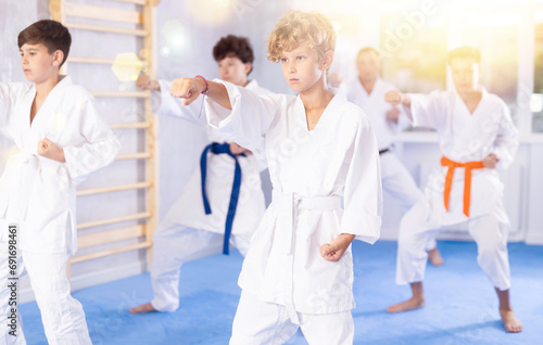 Group lesson in karate or taekwondo for kids in modern gym. Practicing kicks