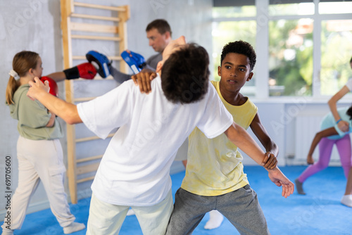 Two boys practicing self-defense techniques in group at gym..