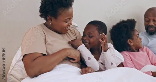 Happy, tickling and black family having fun in bed together at modern home for bonding. Smile, love and African mother and father playing, laughing and being crazy with kids in the bedroom of house. photo