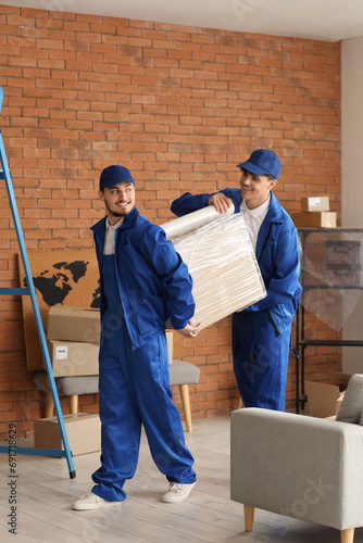 Male movers wrapping box wi...