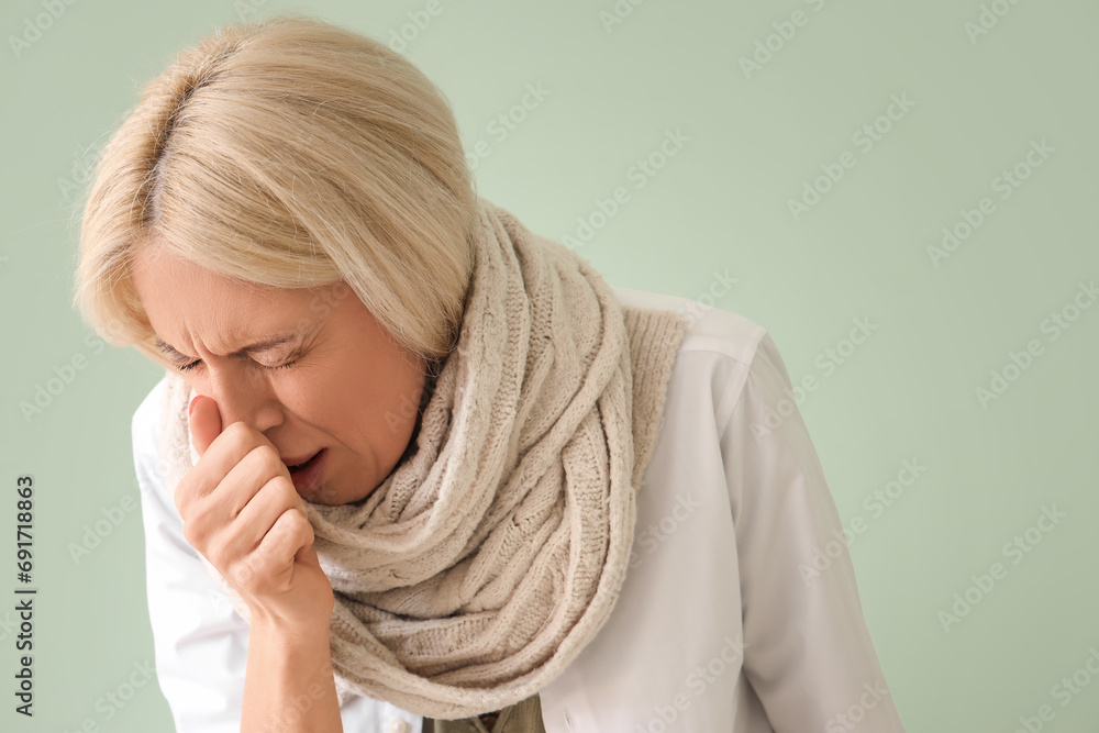 Ill mature woman with runny nose on green background, closeup Ill mature woman with runny nose on green background, closeup