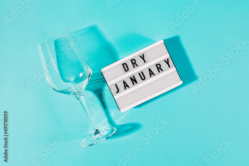 Text Dry January on the decorative lightbox and empty wine glass isolated on blue background photo