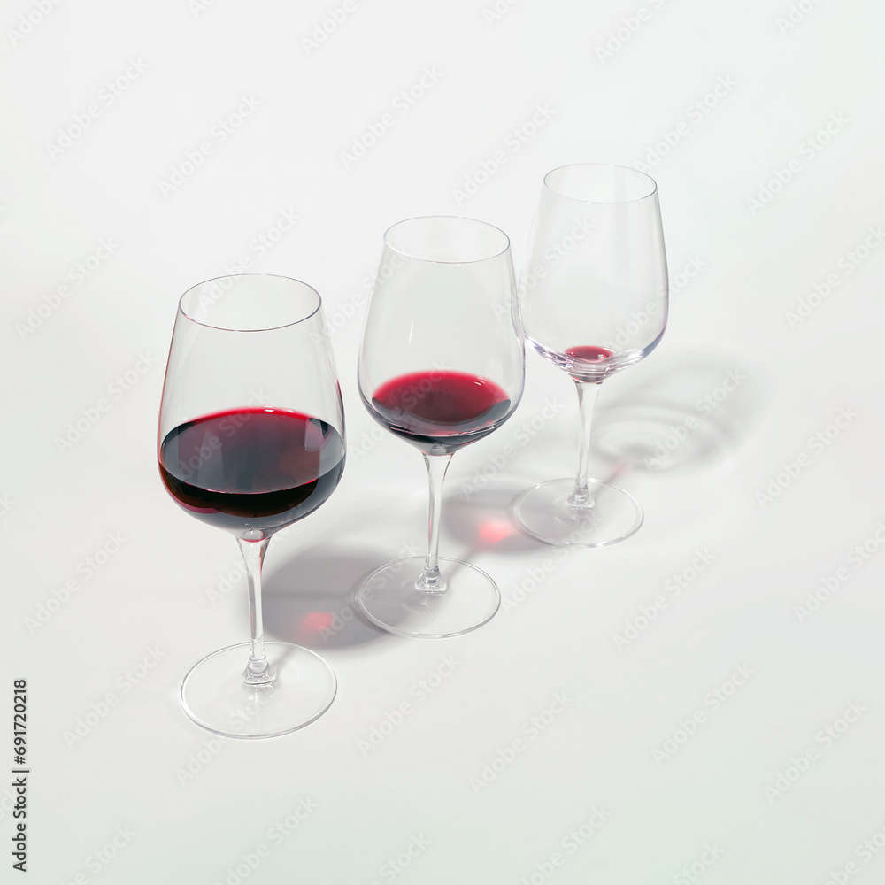 Three glasses with lowering levels of red wine poured, isolated on white. Mindful drinking and alcohol cutback. Three glasses with lowering levels of red wine poured, isolated on white. Mindful drinking and alcohol cutback.