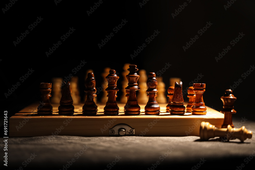 Game board with wooden chess pieces on dark background, closeup Game board with wooden chess pieces on dark background, closeup