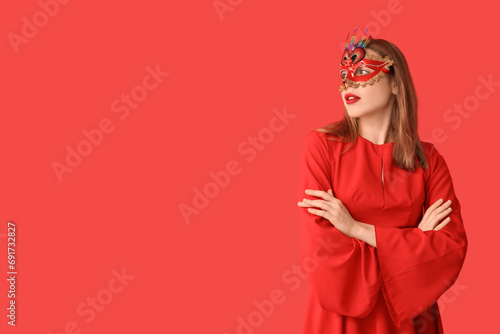 Beautiful young woman in carnival mask on red background photo