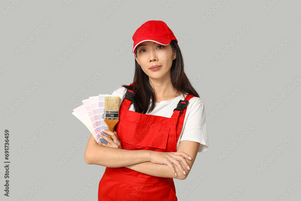 Female Asian painter with paint color palettes and brush on grey background Female Asian painter with paint color palettes and brush on grey background
