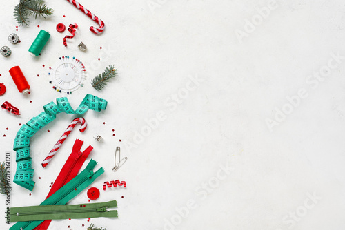 Composition with sewing accessories and Christmas decorations on light background photo