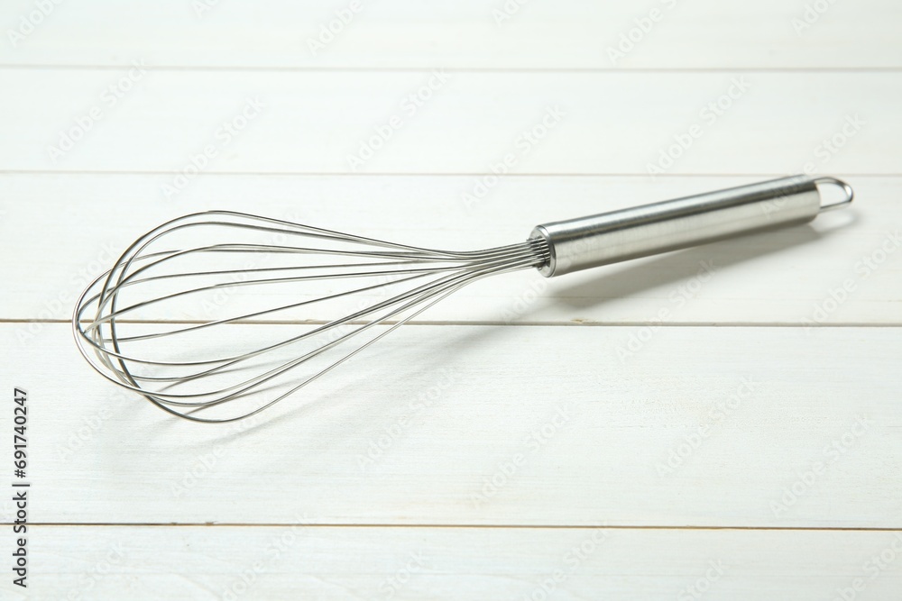 Metal whisk on white wooden table, closeup Metal whisk on white wooden table, closeup