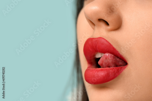 Young woman with bright red lipstick against color background  closeup