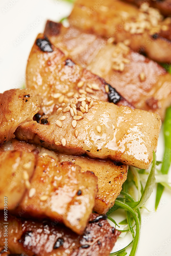 Grilled pork belly with green onions on a plate Grilled pork belly with green onions on a plate