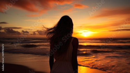 Silhouette of a woman looking at the beach and the ocean at sunset