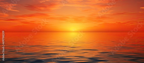 The serene beauty of a sunset as water meets the sky in orange. © AkuAku