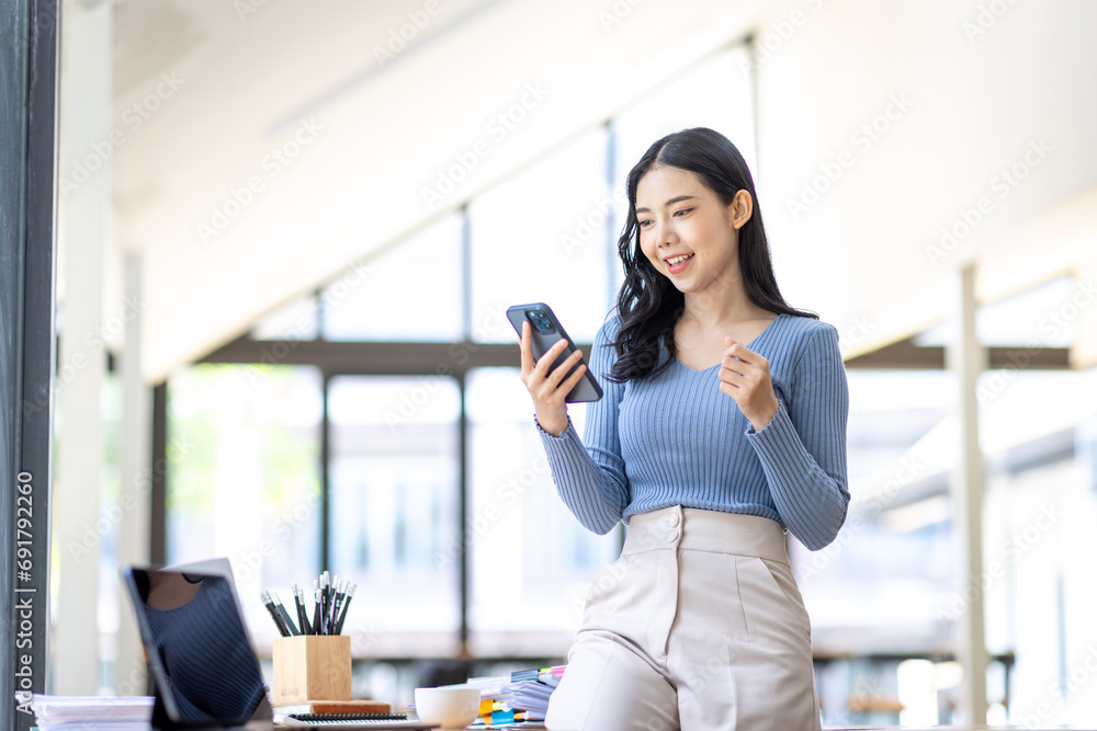 Excited happy Asian woman looking at the phone screen, celebrating an online win, overjoyed young asian female screaming with joy, isolated over a white blur background
