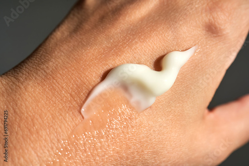 A smear of white moisturizer or sunscreen on a woman s hand.