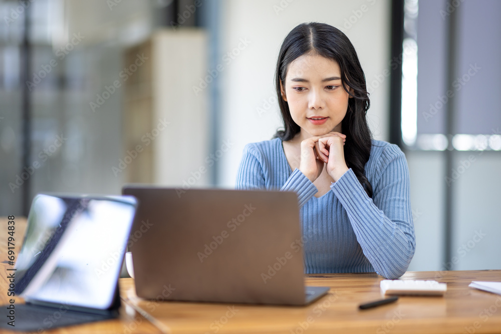 Asian Business woman using calculator and laptop for doing math finance on an office desk, tax, report, accounting, statistics, and analytical research concept

