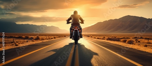 Tapety artystyczne Thrilling shot of a lone motorcyclist on a wide, open road, highlighting the freedom and excitement of riding on a long, straight path.