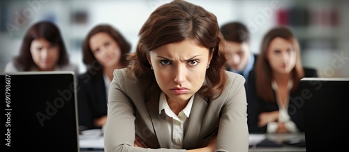 Stressed female team leader at office desk with colleagues.