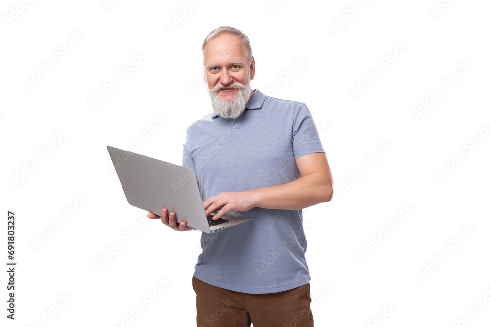 well-groomed elderly man with a gray beard and mustache in a T-shirt holds a laptop well-groomed elderly man with a gray beard and mustache in a T-shirt holds a laptop
