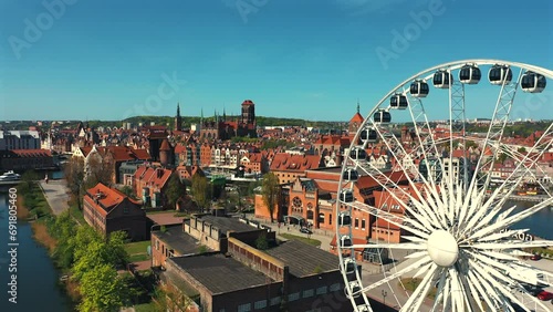 Drone flying arond the Ferris Wheel in Gdańsk with old town and tenements in the background at sunny summer day photo