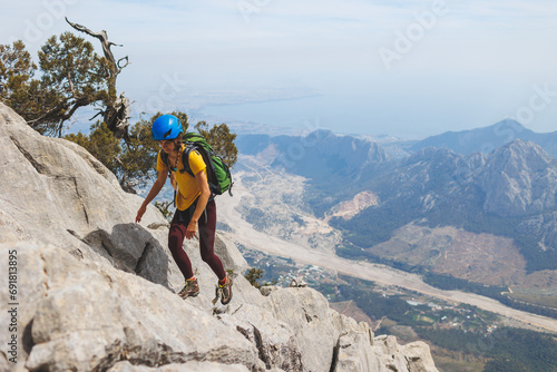climber with a backpack and a helmet goes along a mountain path in the mountains. Girl climber in the mountains.hiking with a backpack in the mountains.