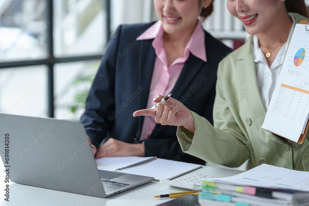 Obraz premium Two confident Asian businesswomen discuss and present ideas via laptop online on new project to analyze joint planning, financial statistics and investment market at office.