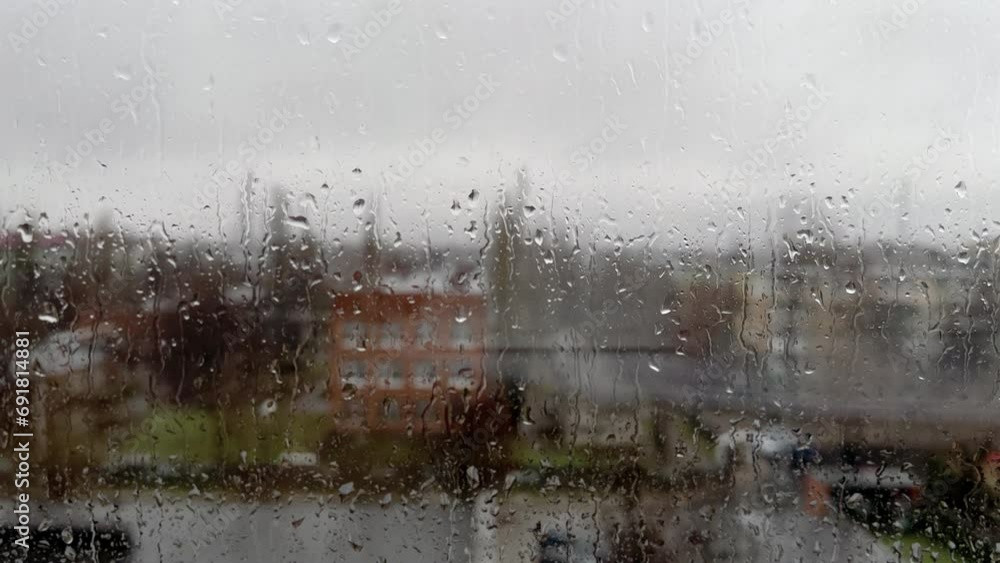 Rainy day in the industrial city. View through wet window with raindrops moment seeing industrial area during rain storm. Background.