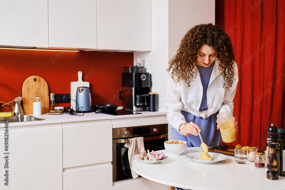 Young woman puts hummus on a plate Young woman puts hummus on a plate