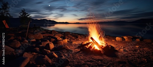 Campfire at night, with sunset, lights, burning embers, and full moon.