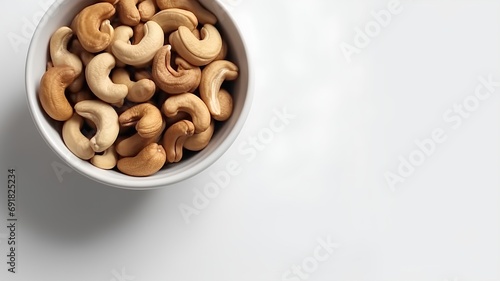Roasted cashew nuts in bowl on white background, top view
