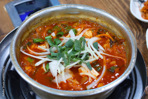 Kimchi Jjigae (Kimchi Stew) Korean food, kimchi soup in hot pot on table.