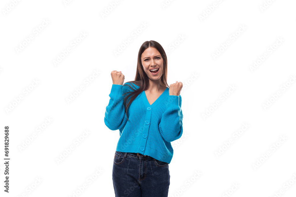 young pretty european brunette woman dressed in a blue cardigan rejoices raising her hands young pretty european brunette woman dressed in a blue cardigan rejoices raising her hands