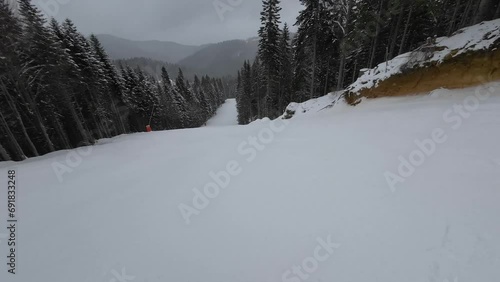 Skiing. Action camera low angle view of skis of skier going downhill on alpine ski on snow slopes in the mountains. Man going downhill on ski having fun on slopes. Winter sport outdoor activity video